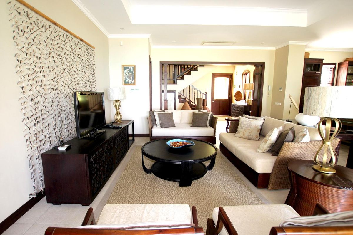 Spacious living room featuring a tray ceiling, tiled flooring, and an open-plan layout leading to the staircase and entrance area.