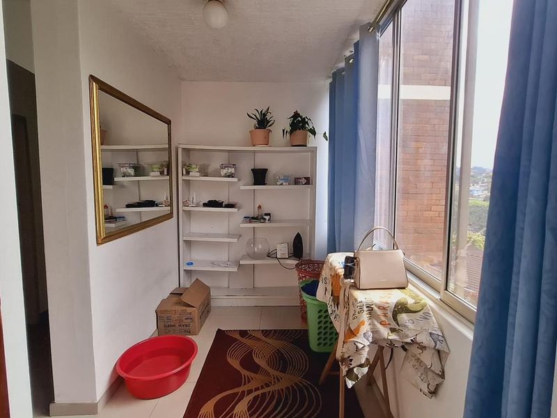 Enclosed balcony area featuring large windows, tiled flooring, and a ceiling light fixture, offering a versatile space with potential for modernization.