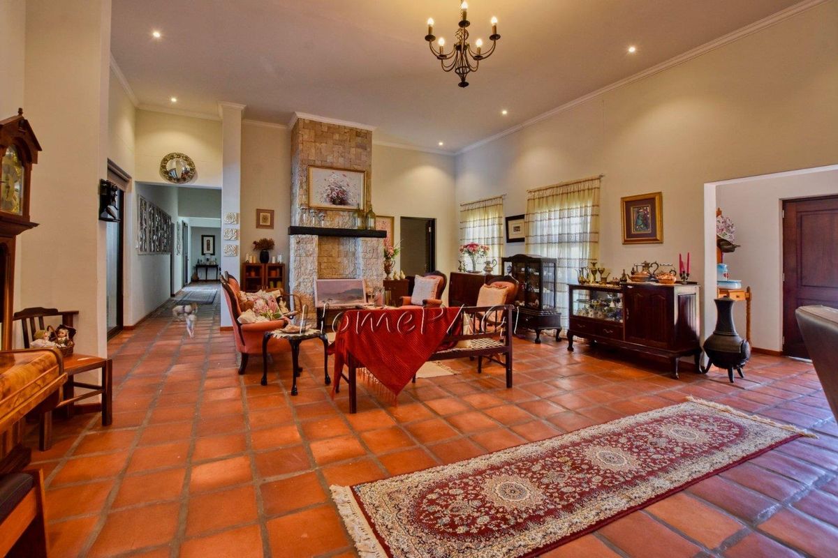 Spacious living room featuring terracotta floor tiles and a prominent stone-clad fireplace, creating a warm and traditional atmosphere.
