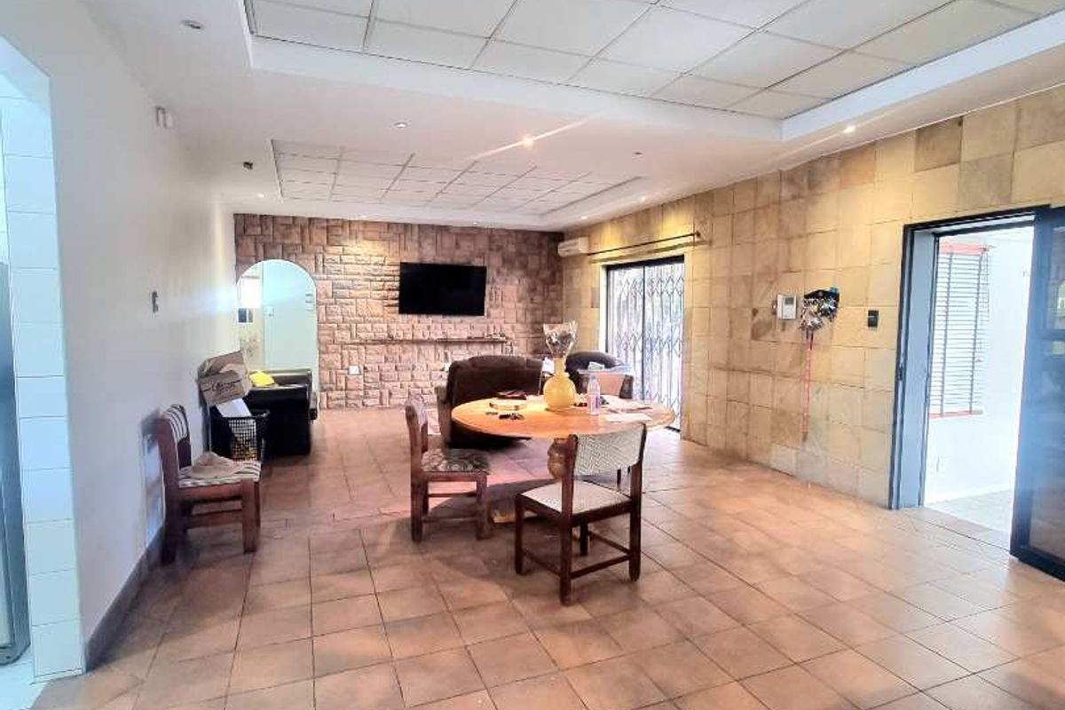 Spacious living area featuring a stone accent wall, tiled flooring, and a suspended ceiling, offering a versatile layout for business or commercial use.