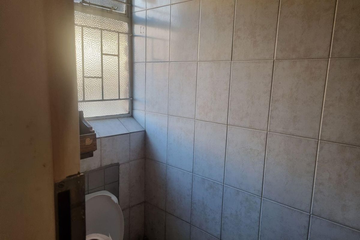 A compact bathroom featuring floor-to-ceiling ceramic wall tiles and a steel-framed window with obscured glass.