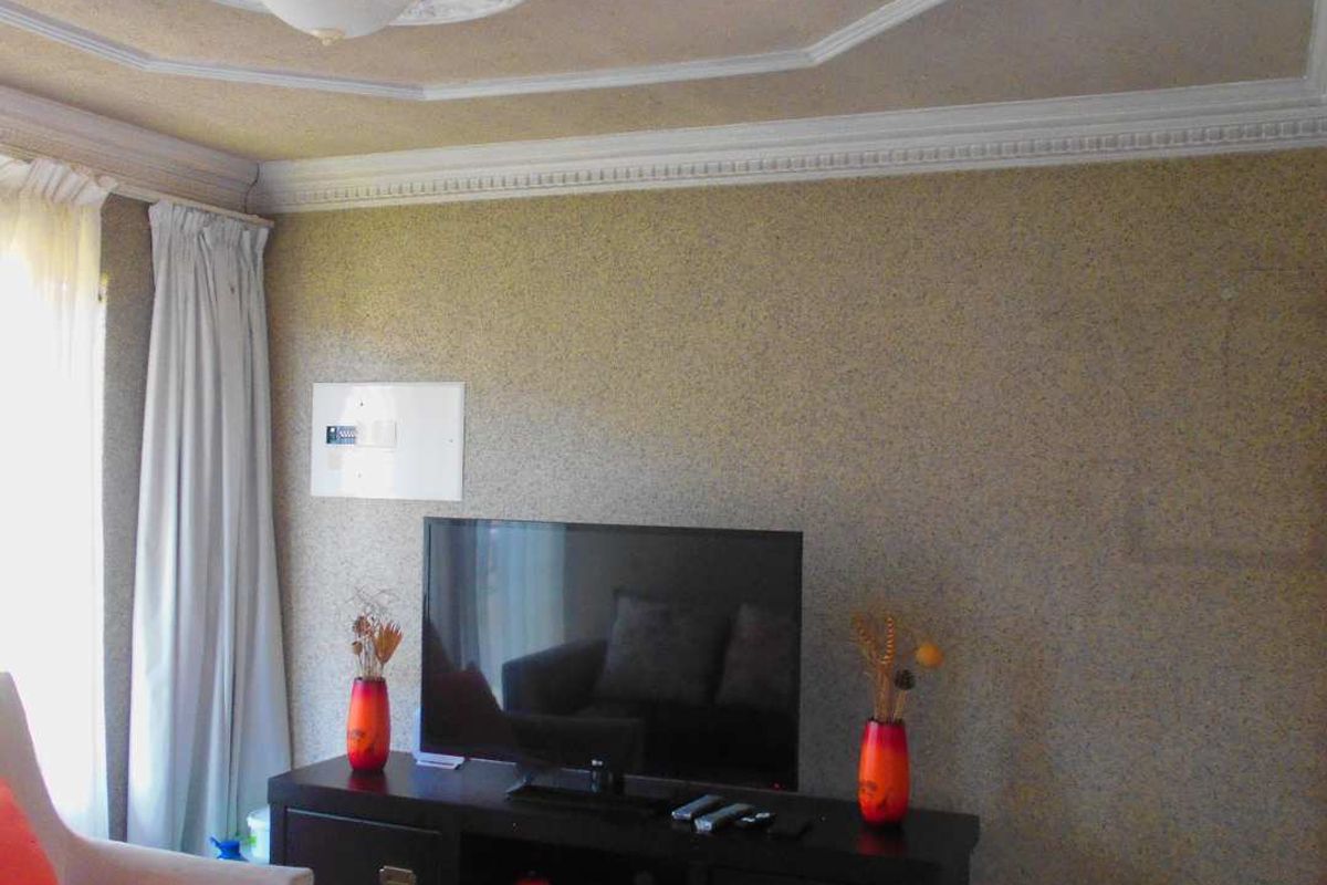 A living room area featuring decorative ceiling molding, a central ceiling rose, and textured wall finishes.