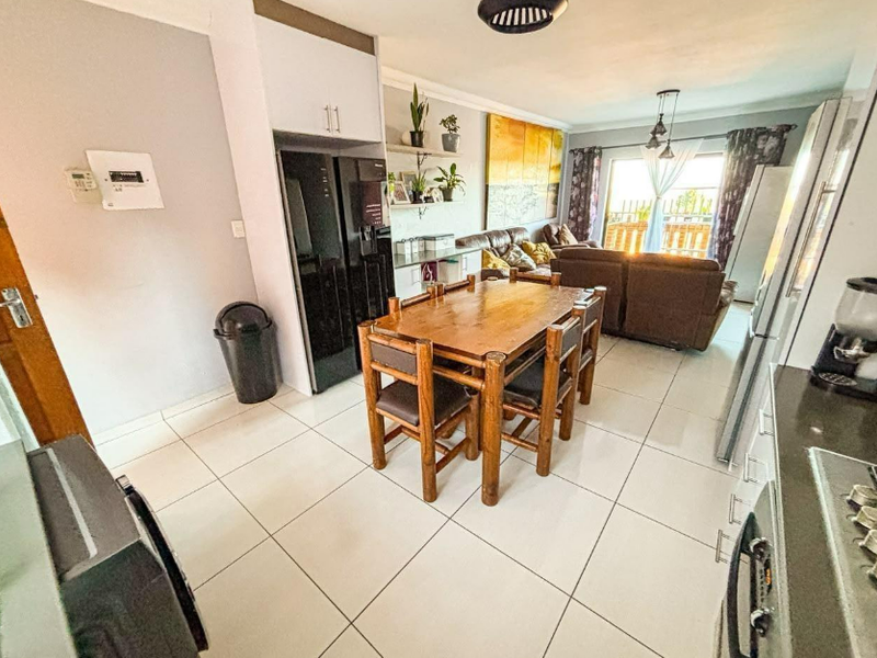 Open-plan living and dining area featuring tiled floors, modern cabinetry, and direct access to an outdoor patio through a sliding glass door.