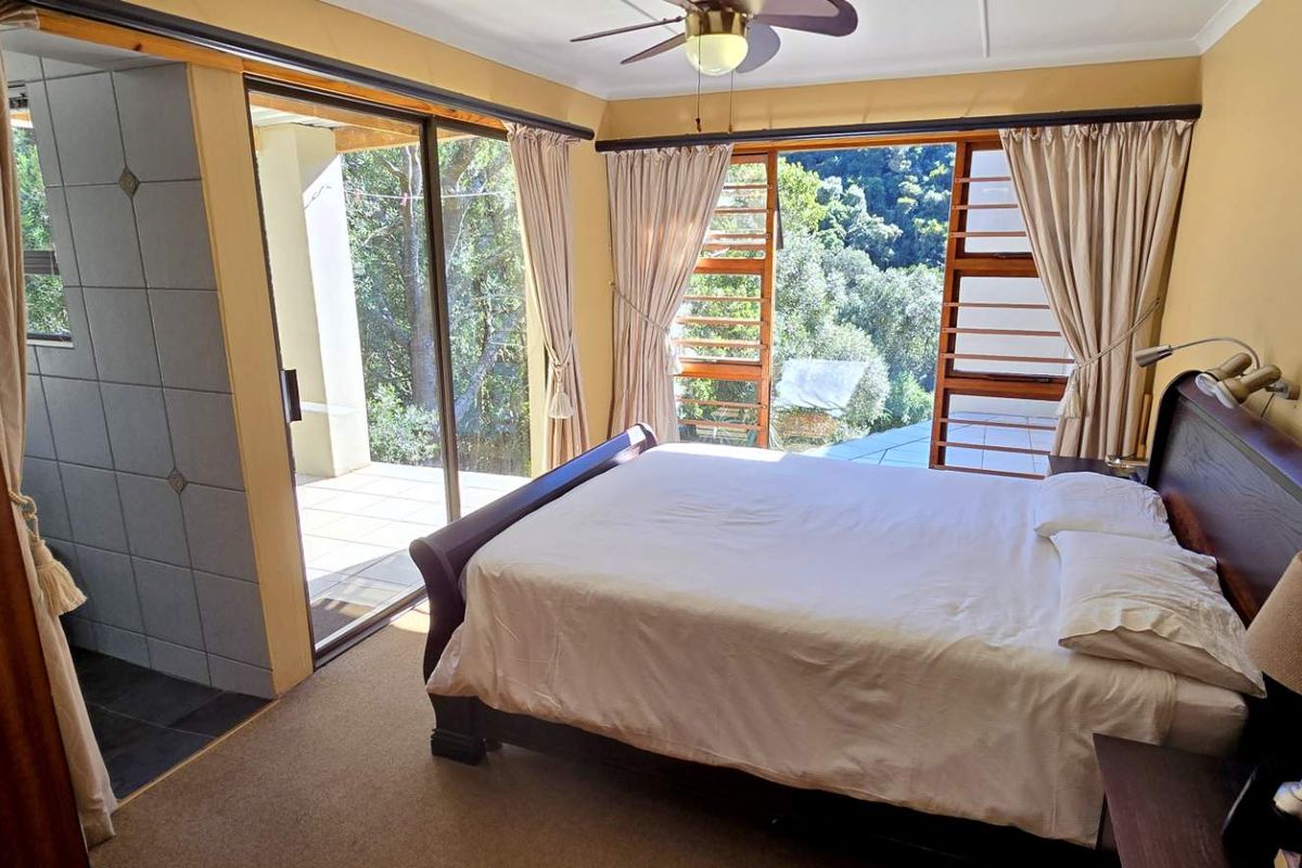 Spacious bedroom featuring large sliding glass doors that open onto a private patio, offering natural light and scenic views of the surrounding landscape.