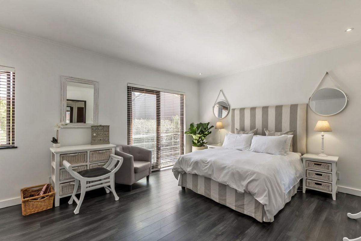 A well-maintained bedroom featuring dark wood-look flooring, recessed ceiling lighting, and a sliding glass door providing natural light.