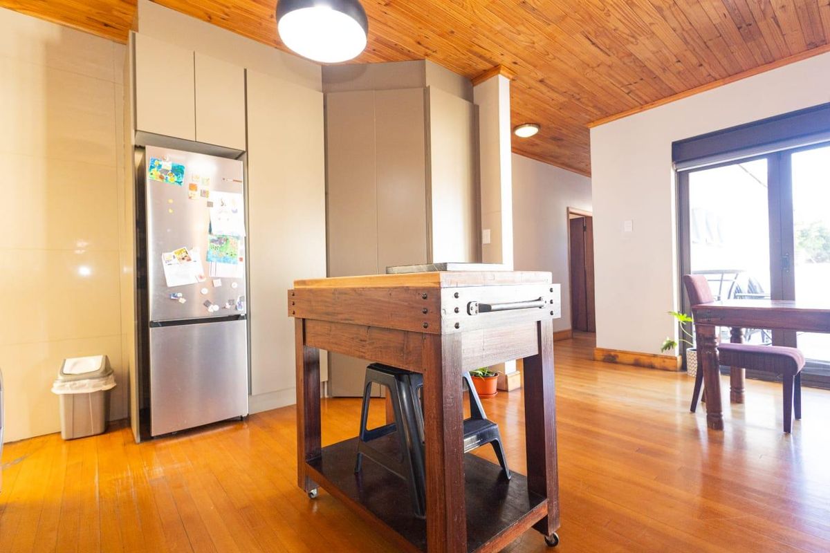 A kitchen area featuring warm timber ceilings and flooring, integrated cabinetry, and direct access to an outdoor space through a sliding glass door.