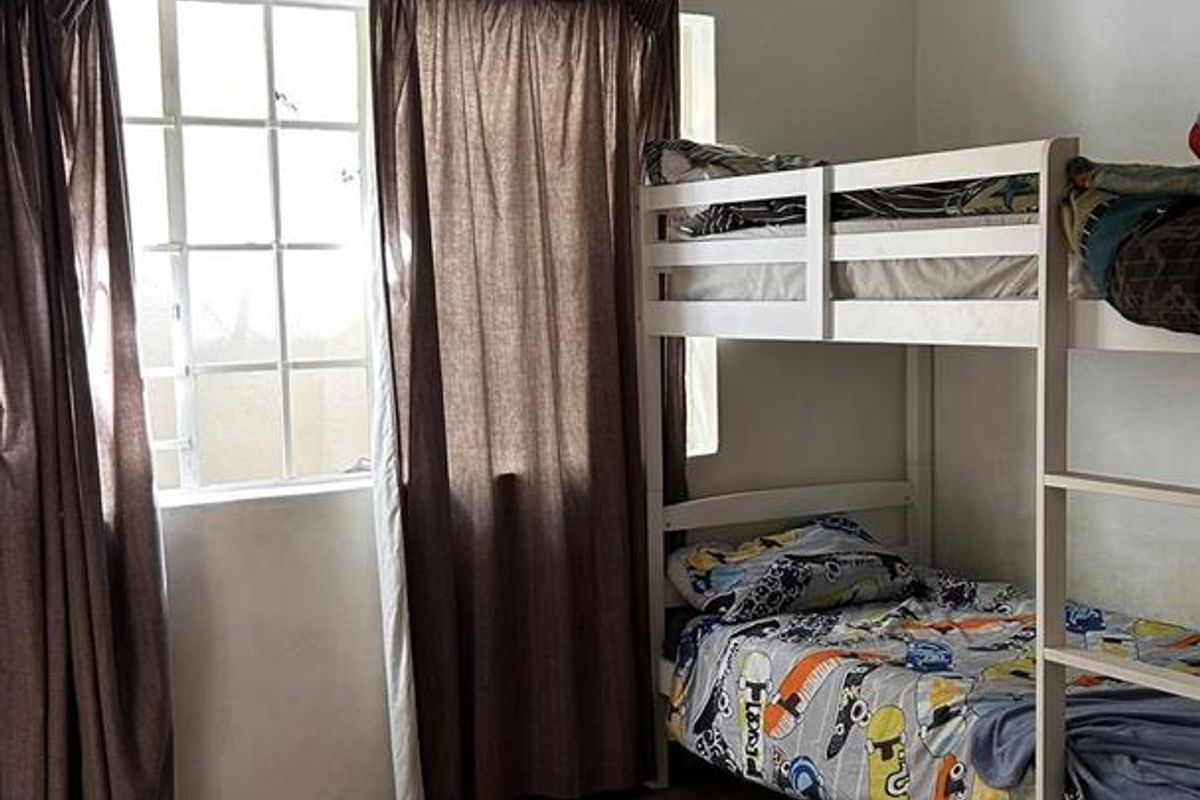 A bedroom featuring a window with natural light, carpeted flooring, and a ceiling-mounted light fixture.
