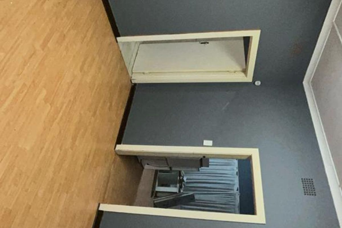 An empty interior room featuring dark grey walls, light wood-look laminate flooring, and two doorways leading to adjacent spaces.