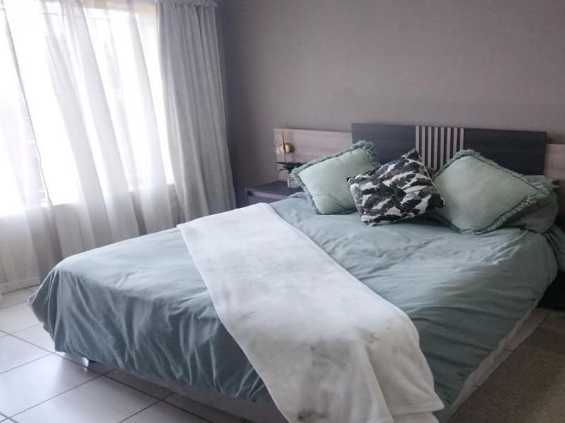 A bedroom featuring a built-in headboard and tiled flooring, offering a functional space with neutral wall tones.