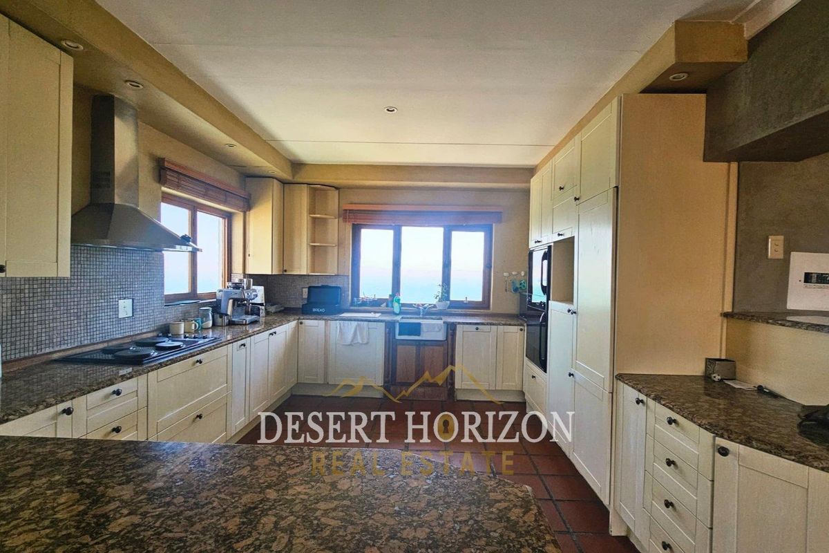 A functional kitchen featuring granite countertops, built-in cabinetry, a stainless steel extractor fan, and a tiled floor.