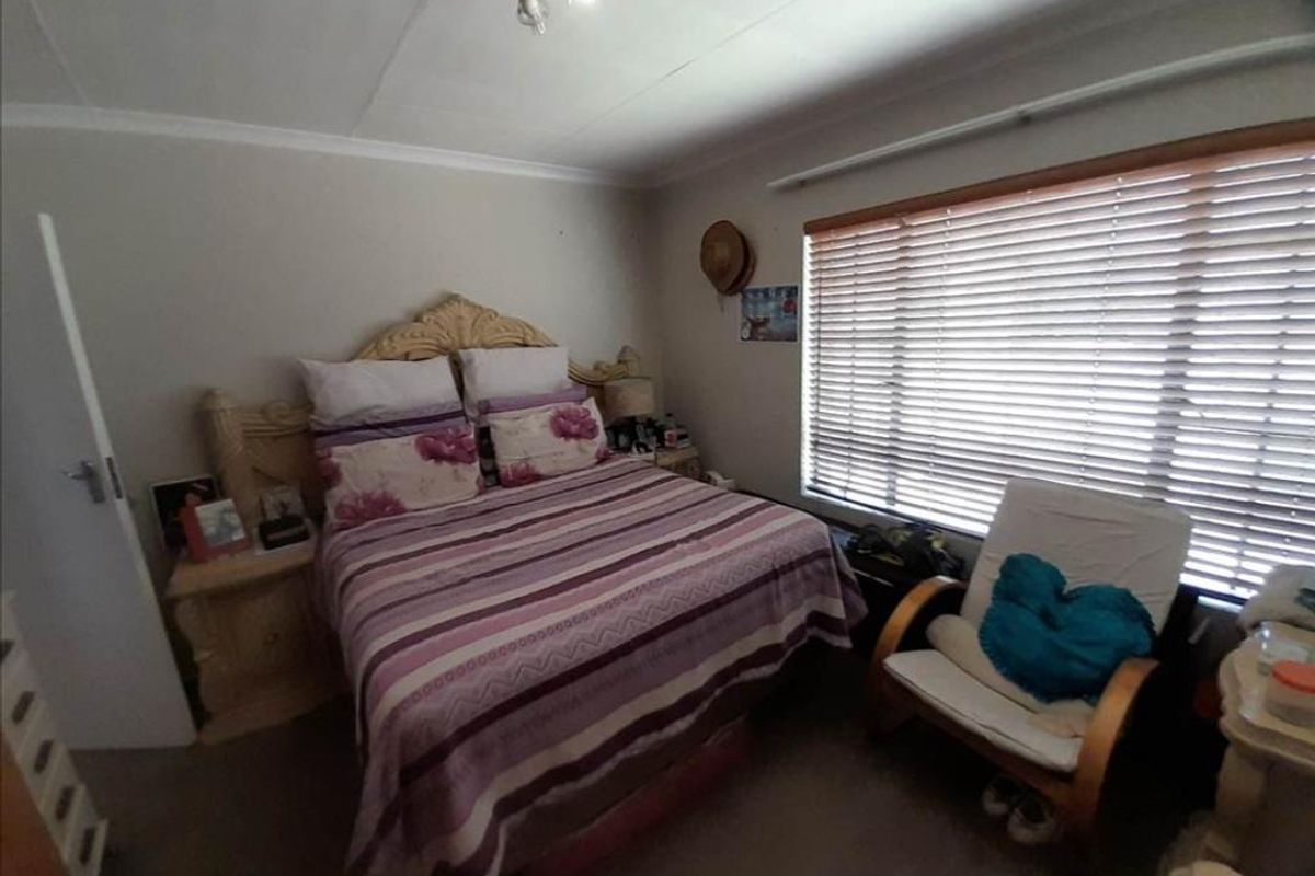 A standard bedroom featuring a large window with fitted blinds and neutral wall finishes.