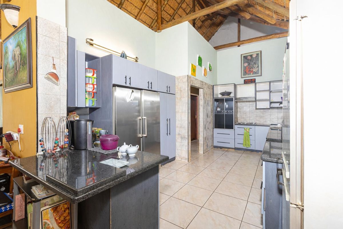 Spacious kitchen featuring granite countertops, built-in cabinetry, and a high vaulted thatched ceiling with exposed timber beams.