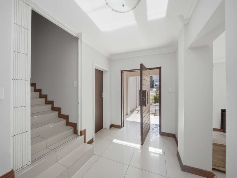 Bright and spacious entrance hall featuring tiled flooring, a modern staircase, and clean neutral finishes, providing a welcoming transition into the home.