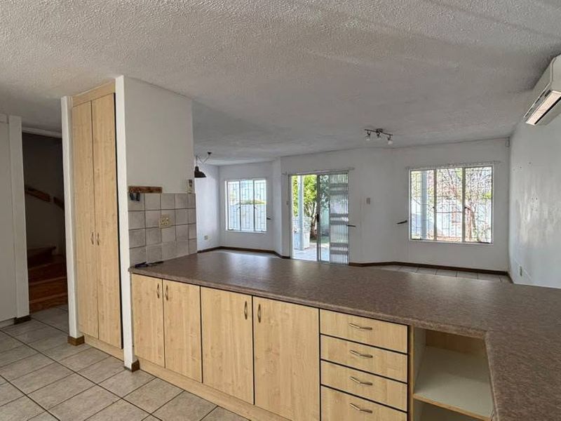 Open-plan kitchen and living area featuring tiled floors, built-in cabinetry, and direct access to the rear patio through sliding glass doors.