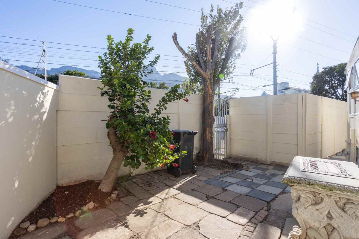 A private rear courtyard area featuring stone paving, enclosed by precast concrete boundary walls and a secure metal pedestrian gate.