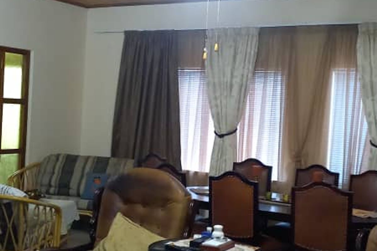 A living and dining area featuring a timber-clad ceiling, ceiling fan, and large windows with curtains.