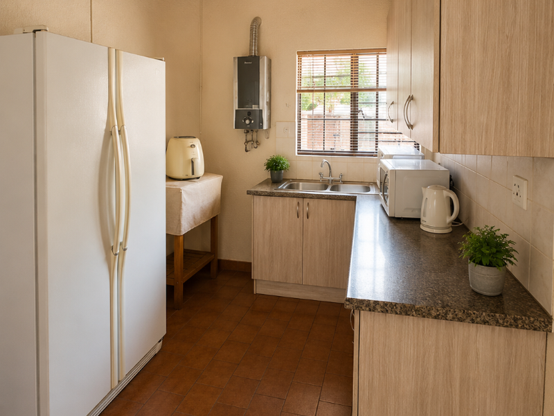 Compact kitchen featuring light wood-look cabinetry, granite-style countertops, a stainless steel sink, and a distinctive exposed thatch ceiling.
