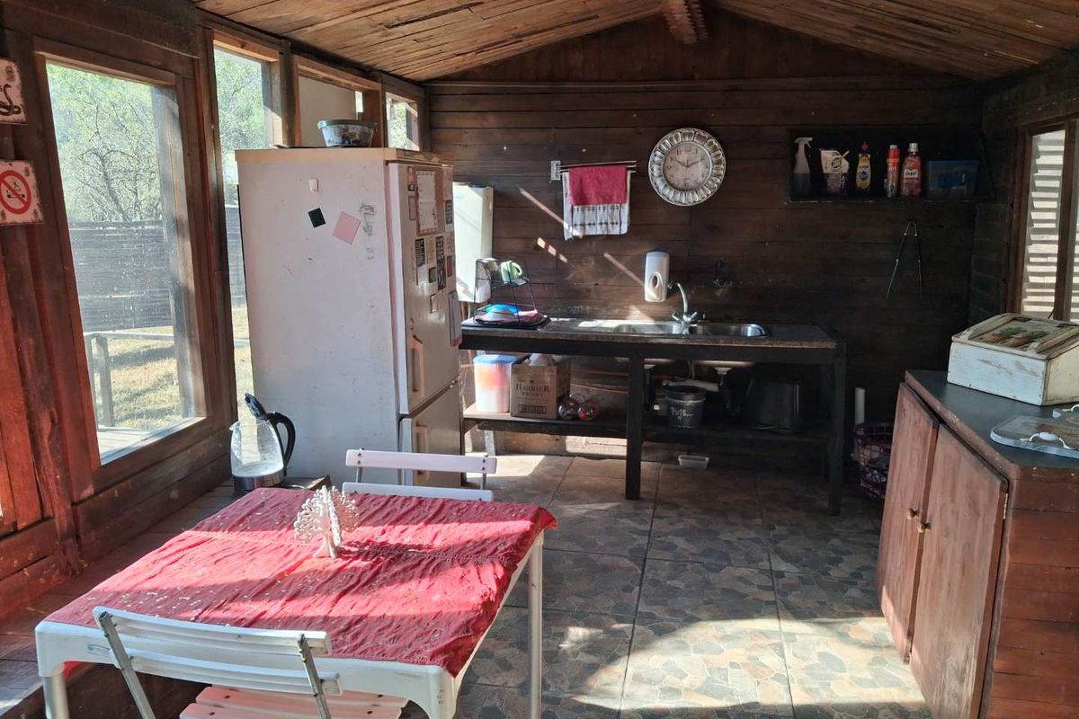 Rustic kitchen area featuring timber wall and ceiling cladding, tiled flooring, and a functional sink station within a cabin-style structure.