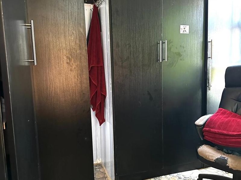 Bedroom featuring dark wood-look built-in cupboards and decorative pebble-style floor tiling.