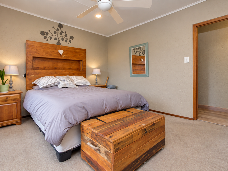 A well-maintained bedroom featuring neutral wall tones, carpeted flooring, a ceiling fan, and recessed lighting, providing a comfortable and functional living space.