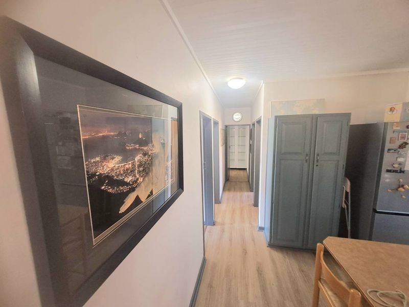 A functional hallway featuring light-toned laminate flooring, panelled ceilings, and multiple internal door access points.