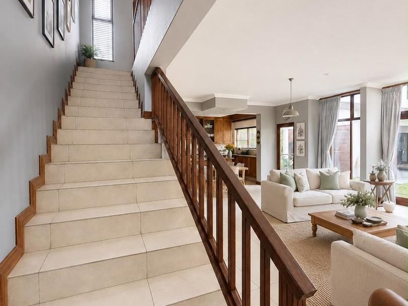 Spacious open-plan living area featuring a tiled staircase with timber balustrade, flowing into a bright living space and kitchen with modern finishes.