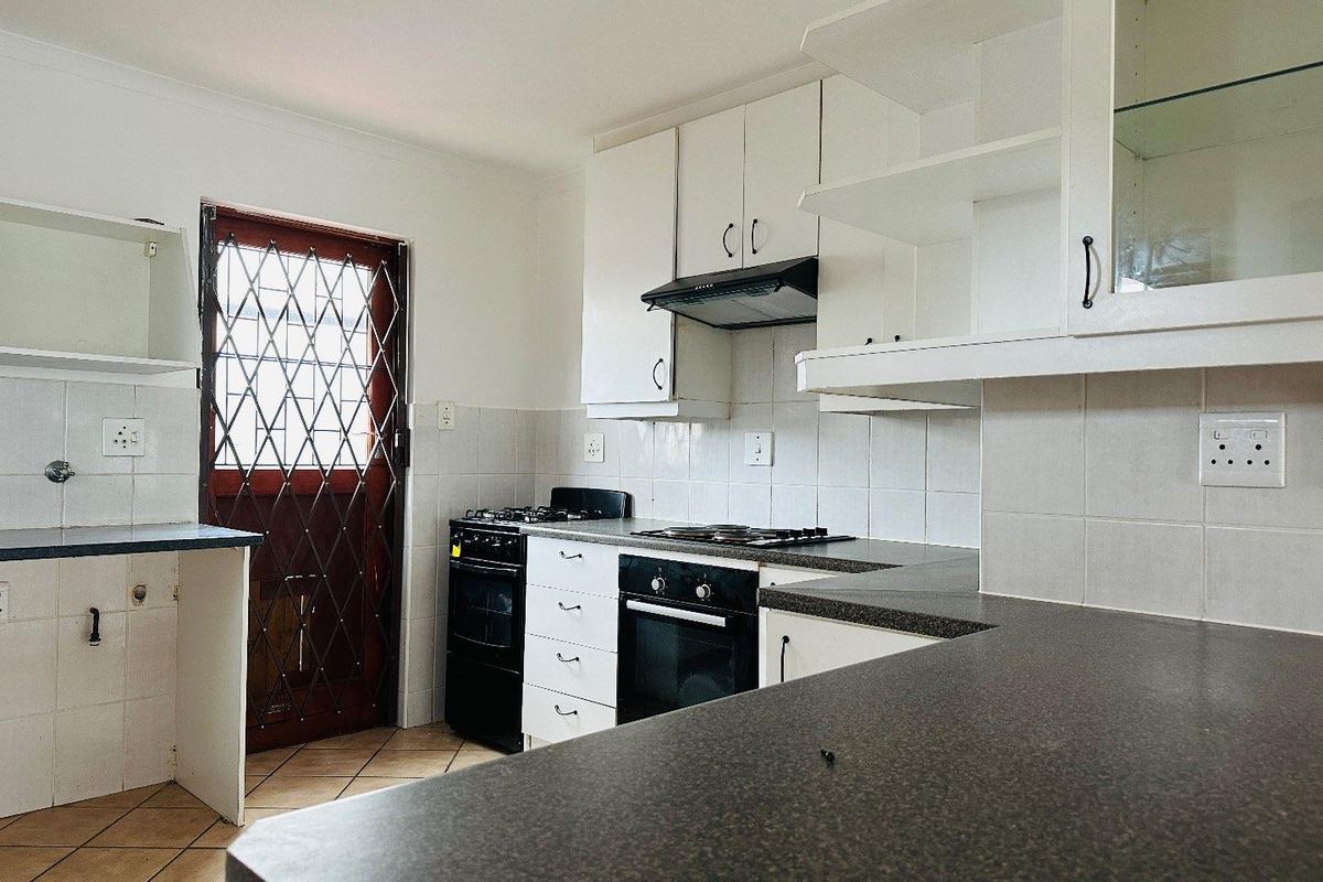 A functional kitchen featuring built-in cabinetry, laminate countertops, a gas hob, and an integrated oven, with direct access to an exterior security door.