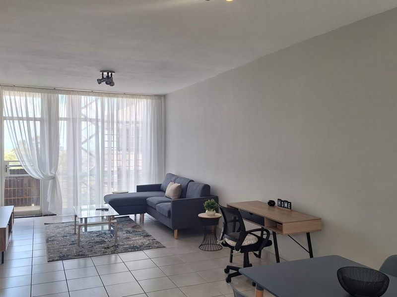 A bright and spacious living area featuring neutral tiled flooring and large sliding glass doors that provide ample natural light.