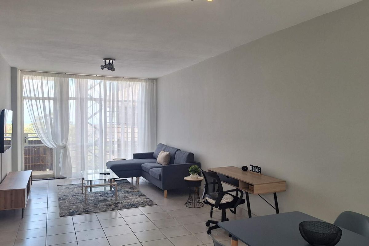 A bright and spacious living area featuring neutral tiled flooring and large sliding glass doors that provide ample natural light.