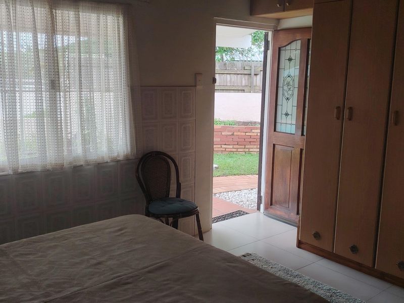Bedroom featuring built-in cupboards, tiled flooring, and direct access to an outdoor patio area through a leaded glass door.
