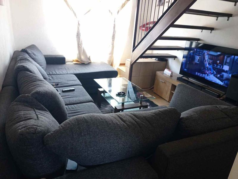 A living room area featuring an open staircase with a metal balustrade, providing access to the upper level of the apartment.