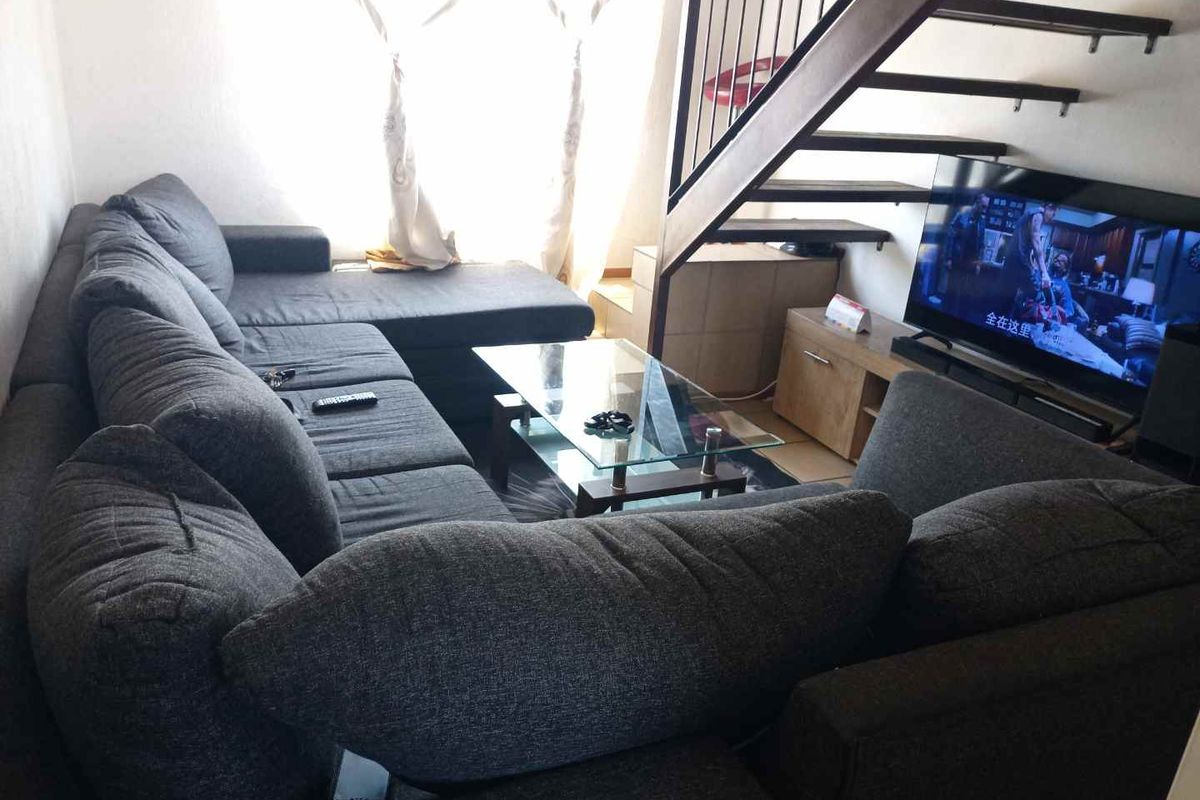 A living room area featuring an open staircase with a metal balustrade, providing access to the upper level of the apartment.