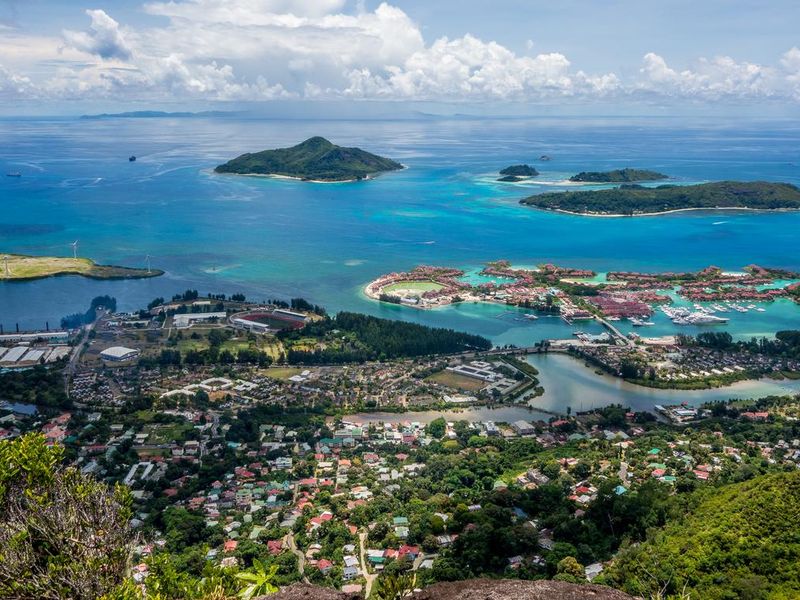 An expansive aerial view overlooking a coastal residential area, marina, and surrounding islands in a tropical setting.