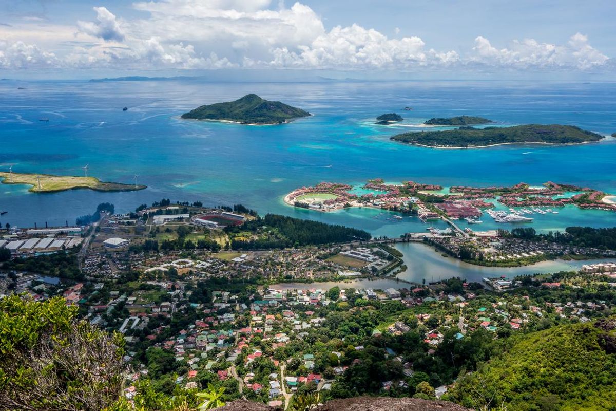 An expansive aerial view overlooking a coastal residential area, marina, and surrounding islands in a tropical setting.