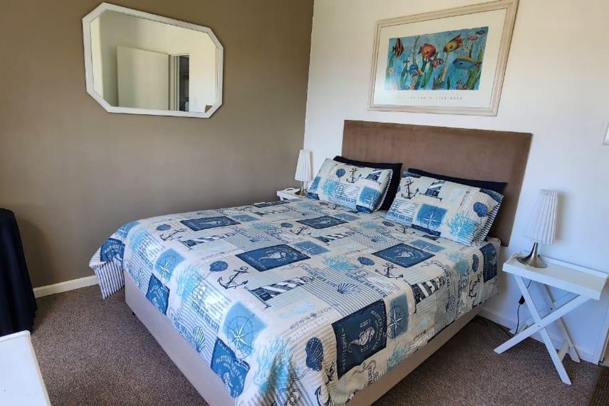 A functional bedroom featuring neutral wall tones, carpeted flooring, and a built-in doorway leading to an adjacent tiled area.
