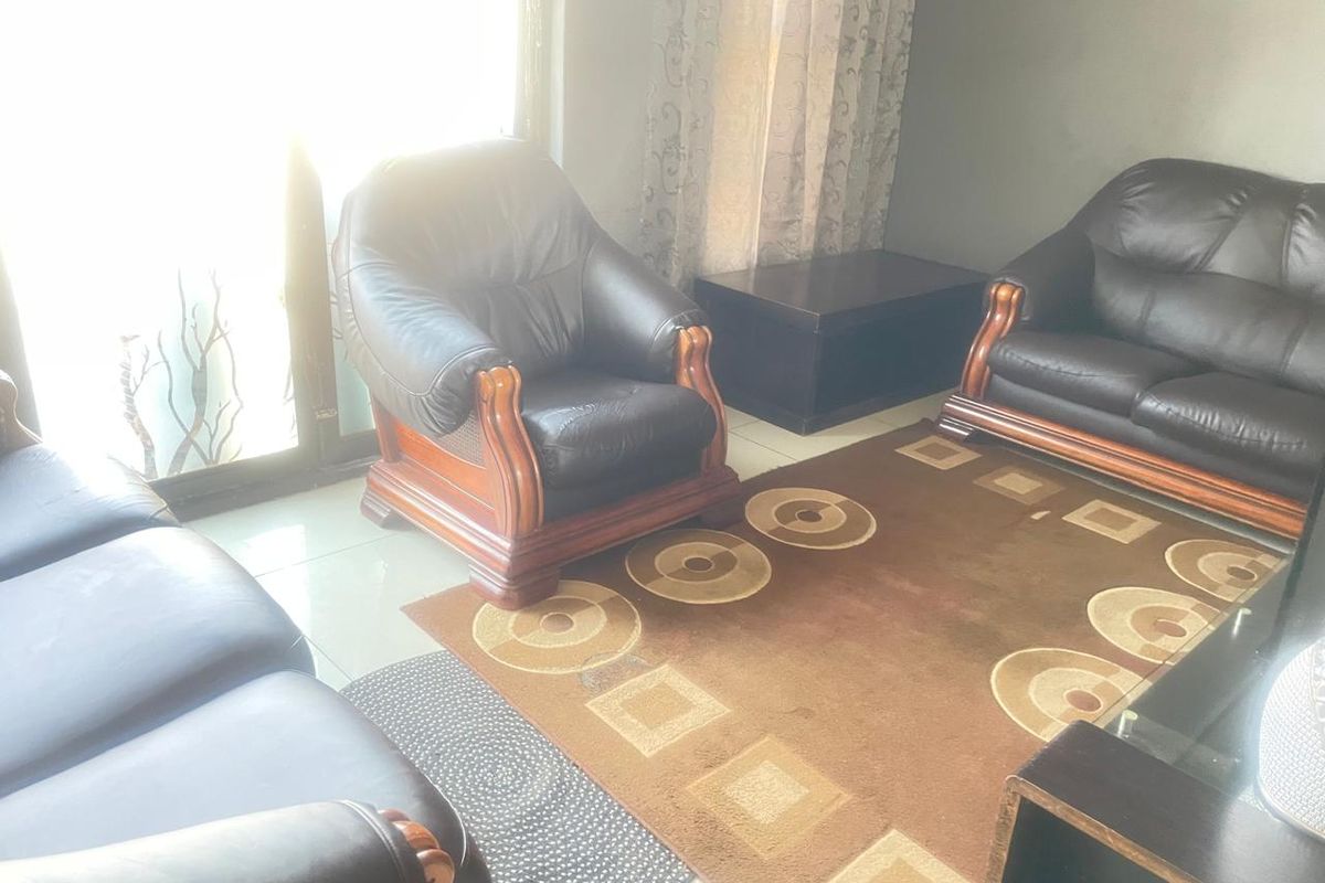 A living room area featuring tiled flooring and a large sliding glass door providing natural light.