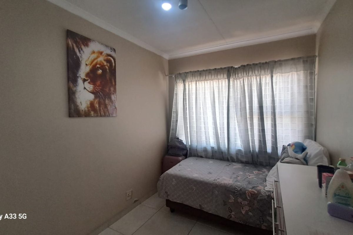 A compact bedroom featuring tiled flooring and neutral wall tones, providing a functional space with natural light through the window.