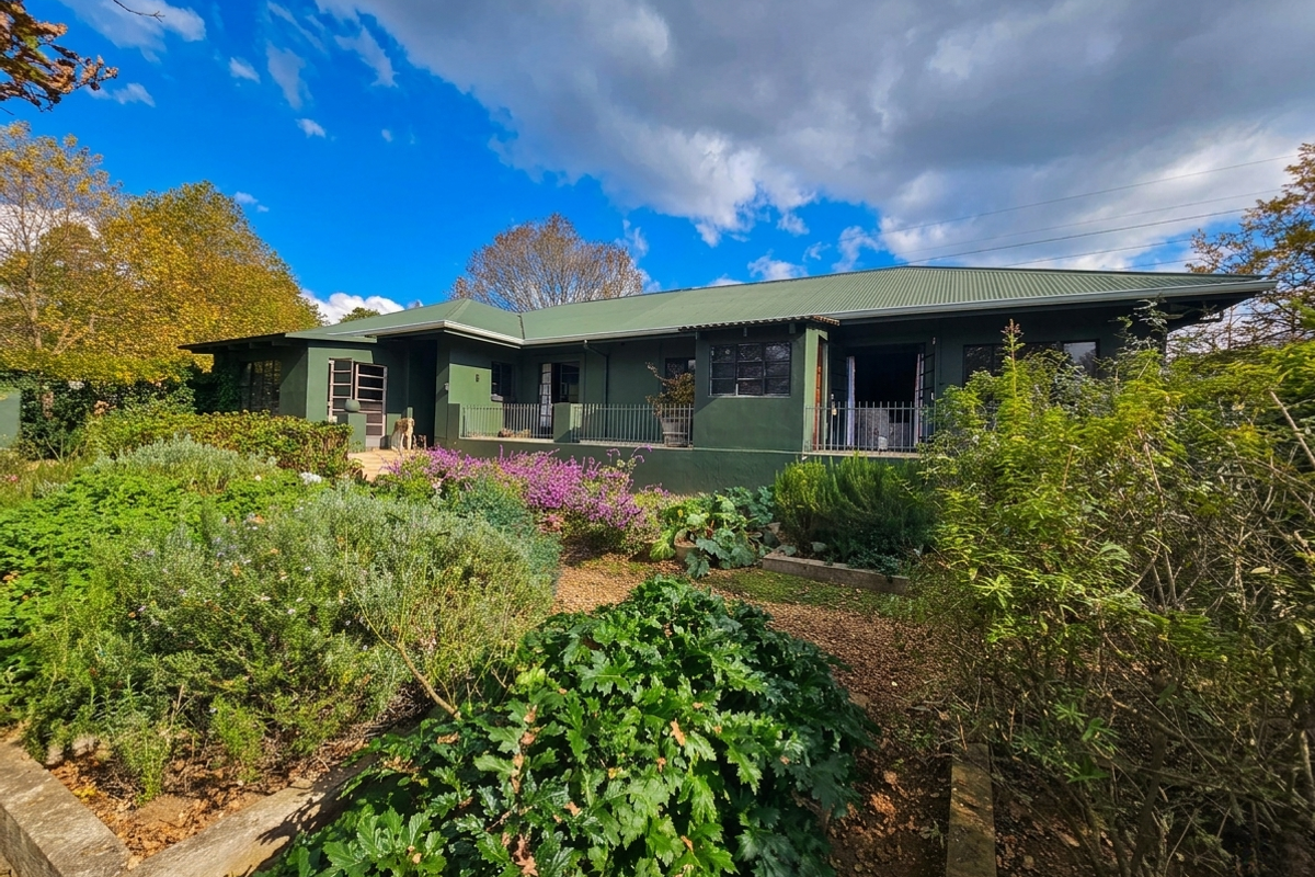 A view of the rear elevation of the house, featuring a covered patio area and established garden landscaping.