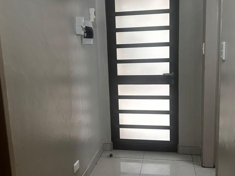 A functional hallway featuring tiled flooring and a modern frosted glass panel door, providing a clean and neutral transition space.