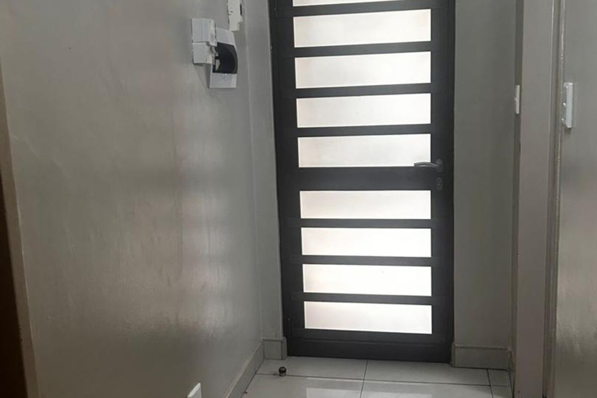 A functional hallway featuring tiled flooring and a modern frosted glass panel door, providing a clean and neutral transition space.
