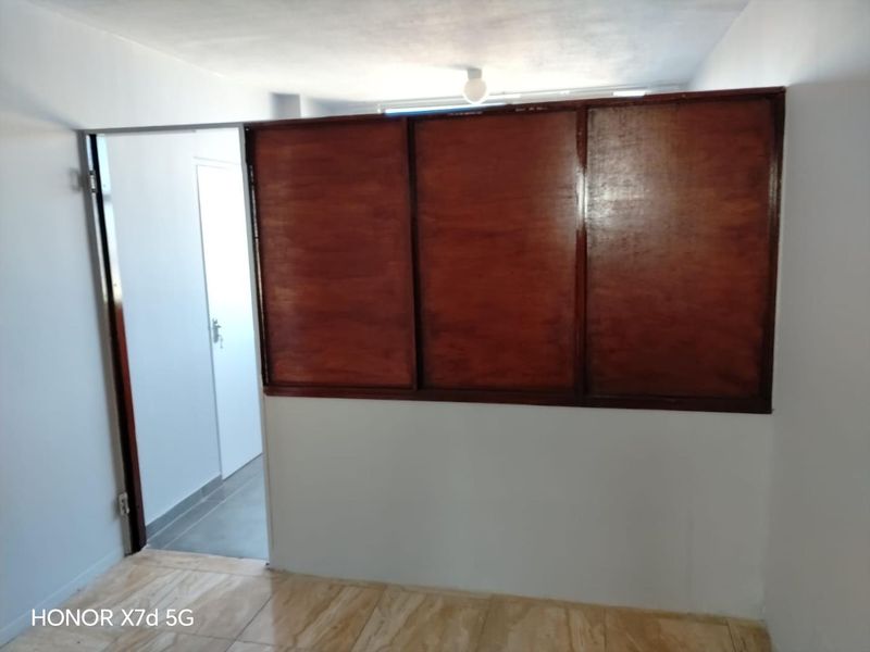 An empty bedroom featuring tiled flooring and a prominent wooden partition wall, offering a blank canvas for potential interior updates and modernization.