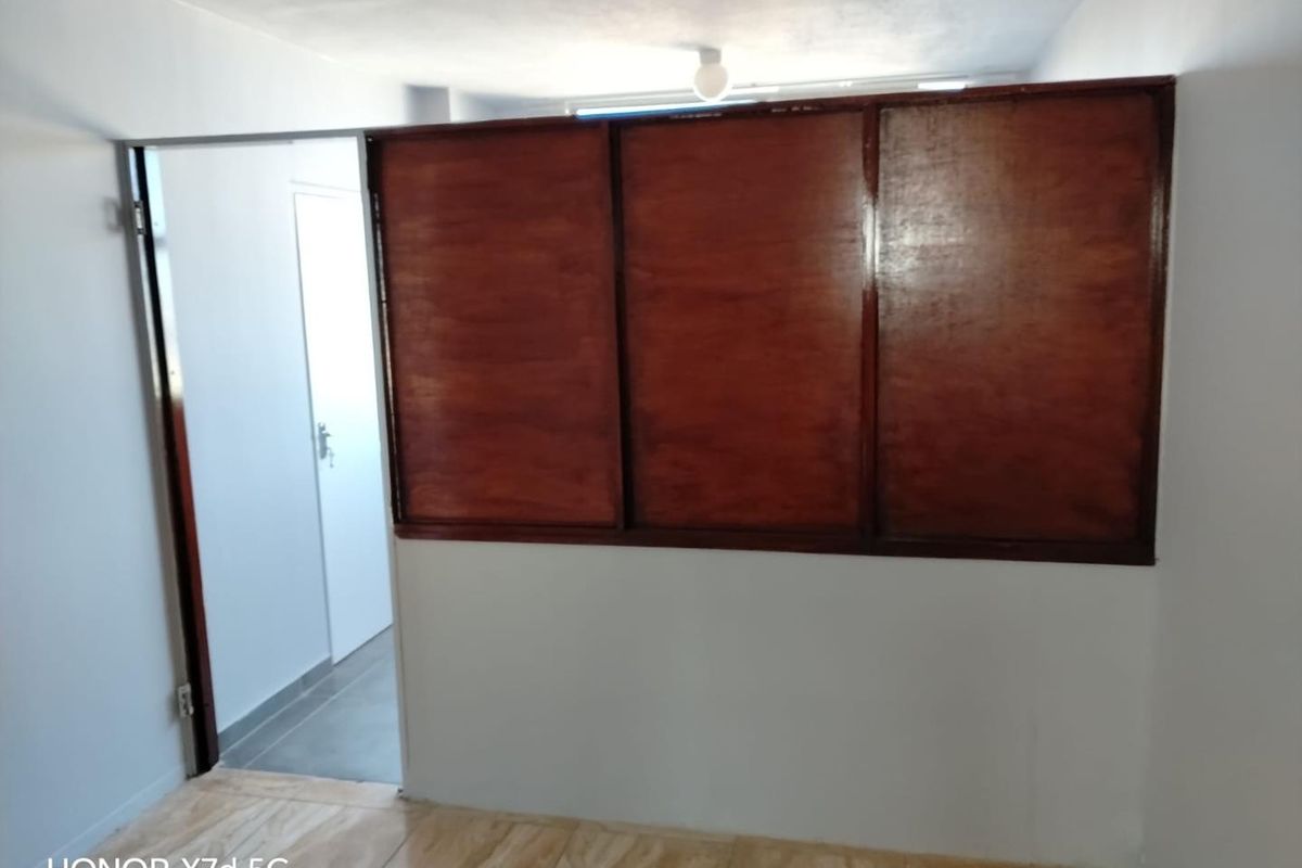 An empty bedroom featuring tiled flooring and a prominent wooden partition wall, offering a blank canvas for potential interior updates and modernization.