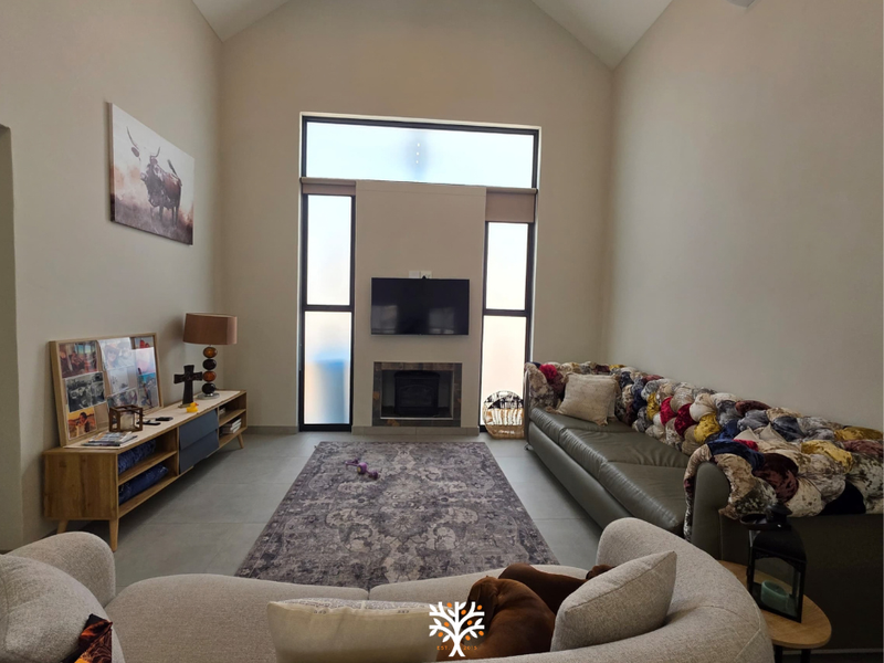 Spacious living room featuring a high vaulted ceiling, tiled flooring, a built-in fireplace, and a wall-mounted air conditioning unit.