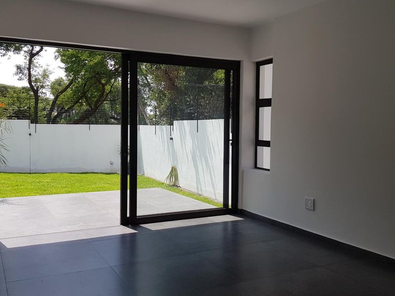 Bright and modern living area featuring large sliding glass doors that open onto a private patio and garden space.