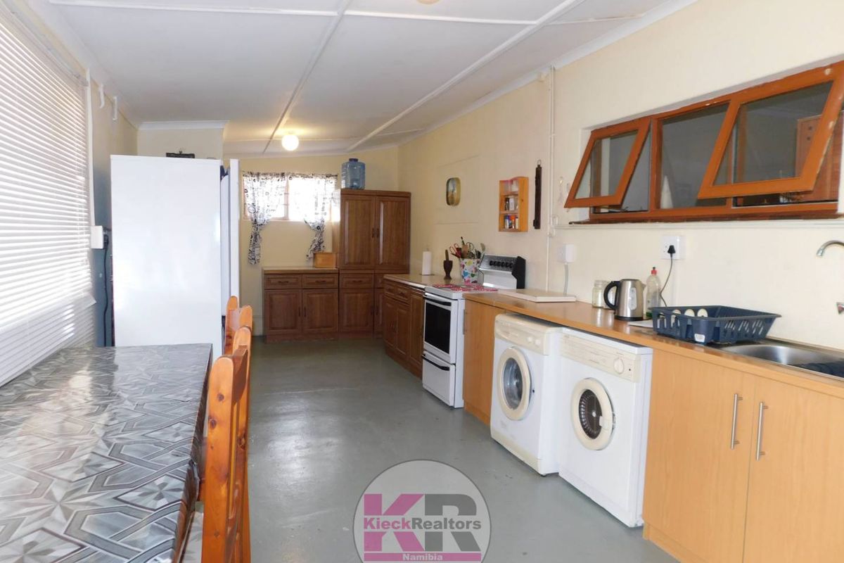 Functional kitchen area featuring built-in cabinetry, laminate countertops, and space for laundry appliances, offering potential for modernization and layout optimization.
