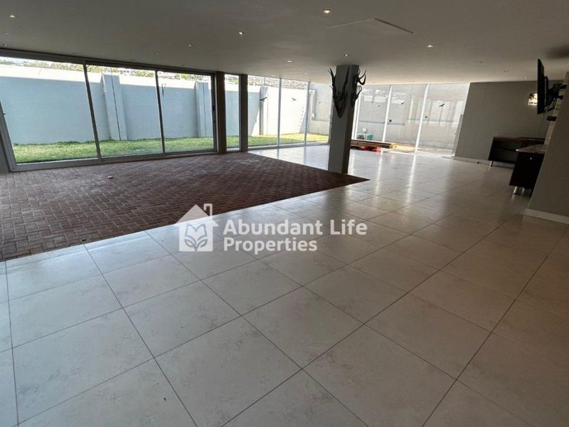 Spacious open-plan living area featuring large format floor tiles, recessed lighting, and expansive sliding glass doors opening to the rear garden.