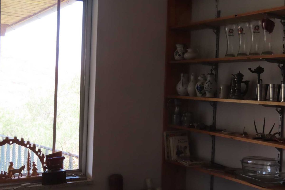 A room featuring built-in wooden shelving units and a large window providing natural light and access to an outdoor balcony area.