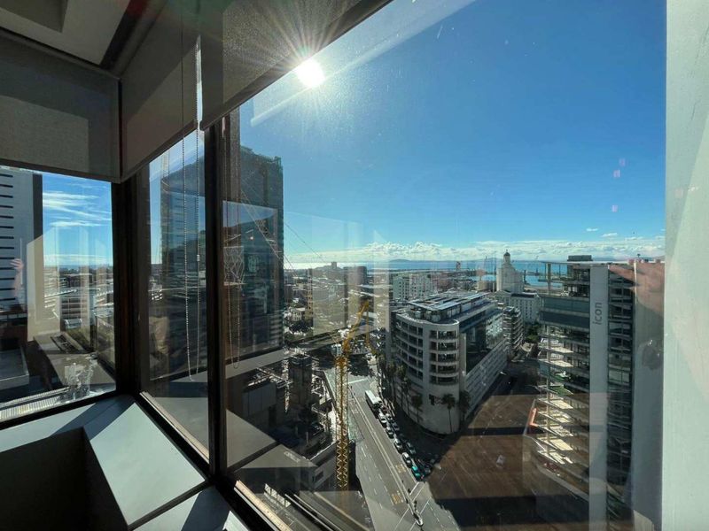 An elevated office view overlooking the city skyline and surrounding urban infrastructure through large floor-to-ceiling windows.