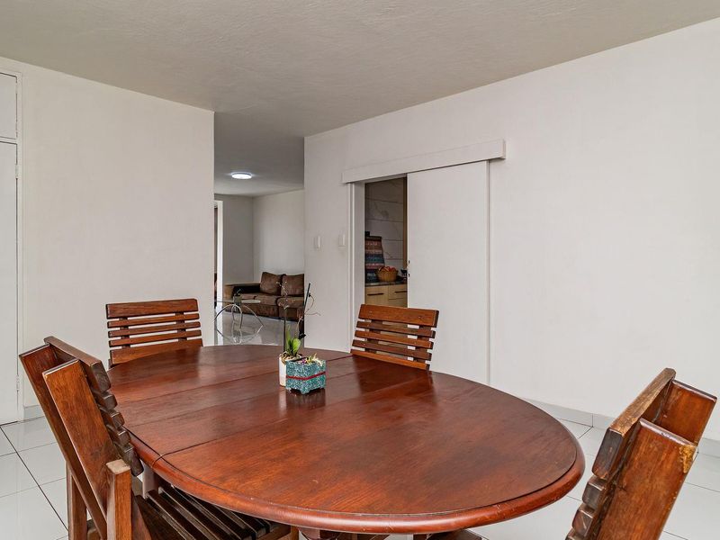 A dining area featuring tiled flooring, a sliding door, and a built-in storage cupboard, providing a functional space for meals.