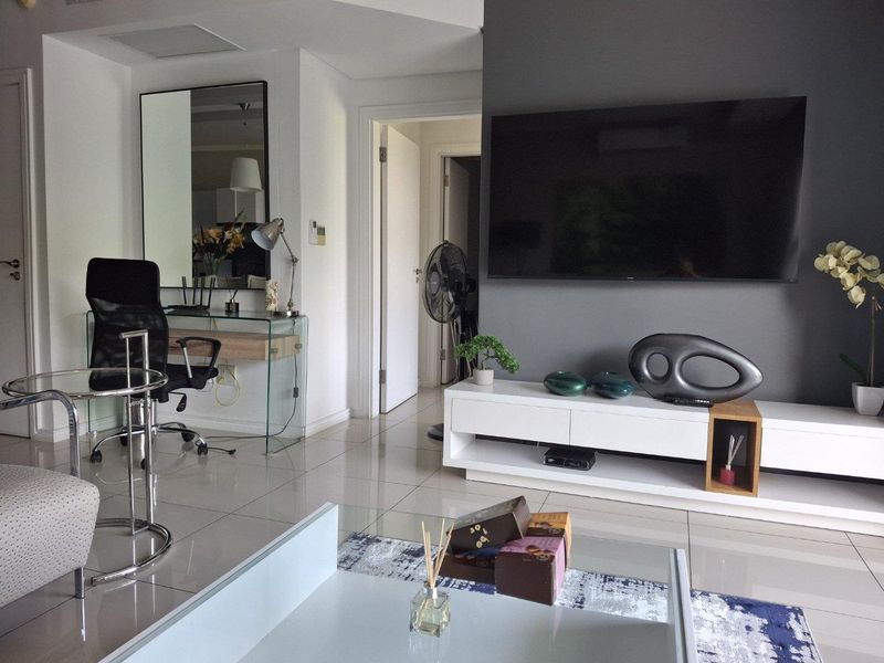 A modern living room featuring polished tiled flooring, a dark grey accent wall, and recessed ceiling lighting.